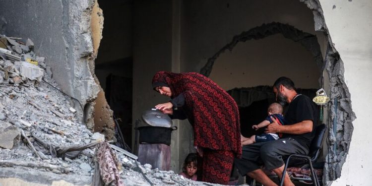 A Palestinian family gathers around a makeshift wood stove in a damaged building in Khan Yunis, southern Gaza © Bashar TALEB / AFP
