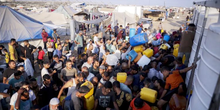 Palestinians displaced by the Israeli bombardment of the Gaza Strip queue for water at a makeshift tent camp in the southern town of Khan Younis, Monday, July 1, 2024. (AP Photo/Jehad Alshrafi)ASSOCIATED PRESS