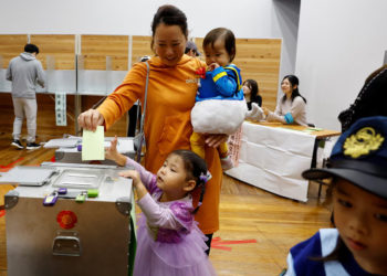 A woman accompanying her children in Halloween costume casts her ballot in the general election at a polling station in Tokyo, Japan October 27, 2024. REUTERS/Kim Kyung-Hoon
