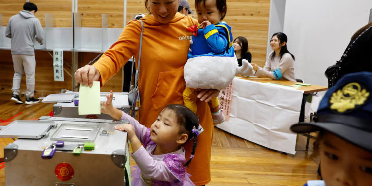A woman accompanying her children in Halloween costume casts her ballot in the general election at a polling station in Tokyo, Japan October 27, 2024. REUTERS/Kim Kyung-Hoon
