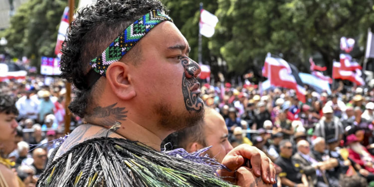 Thousands of people gather outside New Zealand’s parliament to protest a proposed law that would redefine the country’s founding agreement between Indigenous Māori and the British Crown, in Wellington Tuesday, Nov. 19, 2024. (AP Photo/Mark Tantrum) 5 of 20 | New Zealand’s opposition leader Chris Hipkins, left, does a hongi with Hare Arapere as people gathered outside New Zealand’s parliament to protest a proposed law that would redefine the country’s founding agreement between Indigenous Māori and the British Crown, in Wellington Tuesday, Nov. 19, 2024. (AP Photo/Mark Tantrum) 6 of 20 | Hana-Rāwhiti Maipi-Clarke speaks to the thousands of people gathered outside New Zealand’s parliament to protest a proposed law that would redefine the country’s founding agreement between Indigenous Māori and the British Crown, in Wellington Tuesday, Nov. 19, 2024. (AP Photo/Mark Tantrum) 7 of 20 | Te Haukūnui Hokianga plays a conch shell ahead of a protest at New Zealand’s parliament against a proposed law that would redefine the country’s founding agreement between Indigenous Māori and the British Crown, in Wellington, New Zealand, Tuesday, Nov. 19, 2024. (AP Photo/Mark Tantrum) 8 of 20 | A man carries a child on his shoulders outside New Zealand’s parliament during a protest against a proposed law that would redefine the country’s founding agreement between Indigenous Māori and the British Crown, in Wellington Tuesday, Nov. 19, 2024. (AP Photo/Mark Tantrum) 9 of 20 | Indigenous Māori gather outside Parliament in Wellington, New Zealand, Tuesday, Nov. 19, 2024. (AP Photo/Mark Tantrum) 10 of 20 | Thousands of people gather outside New Zealand’s parliament to protest a proposed law that would redefine the country’s founding agreement between Indigenous Māori and the British Crown, in Wellington Tuesday, Nov. 19, 2024. (AP Photo/Mark Tantrum) 11 of 20 | A petition is delivered to Member of Parliament Rawiri Waititi, left, outside New Zealand’s parliament during a protest against a proposed law that would redefine the country’s founding agreement between Indigenous Māori and the British Crown, in Wellington Tuesday, Nov. 19, 2024. (AP Photo/Mark Tantrum) 12 of 20 | Members of Te Āti Awa, join thousands of people gathered outside New Zealand’s parliament to protest a proposed law that would redefine the country’s founding agreement between Indigenous Māori and the British Crown, in Wellington Tuesday, Nov. 19, 2024. (AP Photo/Mark Tantrum) 13 of 20 | A protester reacts outside New Zealand’s parliament during a demonstration against a proposed law that would redefine the country’s founding agreement between Indigenous Māori and the British Crown, in Wellington Tuesday, Nov. 19, 2024. (AP Photo/Mark Tantrum) 14 of 20 | Indigenous Māori reacts outside New Zealand’s parliament to protest against a proposed law that would redefine the country’s founding agreement between Indigenous Māori and the British Crown, in Wellington, New Zealand, Tuesday, Nov. 19, 2024. (AP Photo/Mark Tantrum) 15 of 20 | Indigenous Māori people walk through the streets of Wellington, New Zealand to protest against a proposed law that would redefine the country’s founding agreement between Indigenous Māori and the British Crown, Tuesday, Nov. 19, 2024. (AP Photo/Mark Tantrum) 16 of 20 | Protesters march carrying placards to New Zealand’s parliament to demonstrate against a proposed law that would redefine the country’s founding agreement between Indigenous Māori and the British Crown, in Wellington, New Zealand, Tuesday, Nov. 19, 2024. (AP Photo/Mark Tantrum) 17 of 20 | ACT Party leader David Seymour, center, looks on as thousands of people gather outside New Zealand’s parliament to protest a proposed law that would redefine the country’s founding agreement between Indigenous Māori and the British Crown, in Wellington Tuesday, Nov. 19, 2024. (AP Photo/Mark Tantrum) 18 of 20 | Thousands of people gather outside New Zealand’s parliament to protest a proposed law that would redefine the country’s founding agreement between Indigenous Māori and the British Crown, in Wellington Tuesday, Nov. 19, 2024. (AP Photo/Mark Tantrum) 19 of 20 | Thousands of people gather outside New Zealand’s parliament to protest a proposed law that would redefine the country’s founding agreement between Indigenous Māori and the British Crown, in Wellington Tuesday, Nov. 19, 2024. (AP Photo/Mark Tantrum) 20 of 20 | Thousands of people gather outside New Zealand’s parliament to protest a proposed law that would redefine the country’s founding agreement between Indigenous Māori and the British Crown, in Wellington Tuesday, Nov. 19, 2024. (AP Photo/Charlotte Graham-McLay) By CHARLOTTE GRAHAM-McLAY Updated 10:38 AM GMT+6, November 19, 2024 WELLINGTON, New Zealand (AP) — As tens of thousands of marchers crowded the streets in New Zealand’s capital Wellington on Tuesday, the throng of people, flags aloft, had the air of a festival or a parade rather than a protest. They arrived to oppose a law that would reshape the county’s founding treaty between Indigenous Māori and the British Crown. But for many, it was about something more: a celebration of a resurging Indigenous language and identity that colonization had once almost destroyed. “Just fighting for the rights that our tūpuna, our ancestors, fought for,” Shanell Bob said as she waited for the march to begin. “We’re fighting for our tamariki, for our mokopuna, so they can have what we haven’t been able to have,” she added, using the Māori words for children and grandchildren. What was likely the country’s largest-ever protest in support of Māori rights — a subject that has preoccupied modern New Zealand for much of its young history — followed a long tradition of peaceful marches the length of the country that have marked turning points in the history of modern New Zealand. Advertisement “We’re going for a walk!” One organizer proclaimed from the stage as crowds gathered at the opposite end of the city from the nation’s Parliament. Some had traveled the length of the country over the past nine days. Related Stories fowave Lawmakers stage Māori protest in New Zealand's parliament fowave New Zealand's founding treaty is at a flashpoint. Why are thousands protesting for Māori rights? fowave New Zealand PM apologizes to survivors of abuse in state and church care For many, the turnout reflected growing solidarity on Indigenous rights from non-Māori. At bus stops during the usual morning commute, people of all ages and races waited with Māori sovereignty flags. Some local schools said they would not register students as absent. The city’s mayor joined the protest. The bill that marchers were opposing is unpopular and unlikely to become law. But opposition to it has exploded, which marchers said indicated rising knowledge of the Treaty of Waitangi’s promises to Māori among New Zealanders — and a small but vocal backlash from those who are angered by attempts by courts and lawmakers to keep them. Advertisement Māori marching for their rights as outlined in the treaty is not new. But the crowds were larger than at treaty marches before and mood was changed, Indigenous people said. “It’s different to when I was a child,” Bob said. “We’re stronger now, our tamariki are stronger now, they know who they are, they’re proud of who they are.” As the marchers moved through the streets of Wellington with ringing Māori haka — rhythmic chants — and waiata, or songs, thousands more holding signs lined the pavement in support. Some placards bore jokes or insults about the lawmakers responsible for the bill, which would change the meaning of the principles of the 1840 Treaty of Waitangi and prevent them from applying only to Māori — whose chiefs signed the document when New Zealand was colonized. But others read “proud to be Māori” or acknowledged the bearer’s heritage as a non-Māori person endorsing the protest. Some denounced the widespread expropriation of Māori land during colonization, one of the main grievances arising from the treaty. “The treaty is a document that lets us be here in Aotearoa so holding it up and respecting it is really important,” said Ben Ogilvie, who is of Pākehā or New Zealand European descent, using the Māori name for the country. “I hate what this government is doing to tear it down.” Advertisement Police said 42,000 people tried to crowd into Parliament’s grounds, with some spilling into the surrounding streets. People crammed themselves onto the children’s slide on the lawn for a vantage point; others perched in trees. The tone was almost joyful; as people waited to leave the cramped area, some struck up Māori songs that most New Zealanders learn at school. A sea of Māori sovereignty flags in red, black and white stretched down the lawn and into the streets. But marchers bore Samoan, Tongan, Indigenous Australian, U.S., Palestinian and Israeli flags, too. At Parliament, speeches from political leaders drew attention to the reason for the protest — a proposed law that would change the meaning of words in the country’s founding treaty, cement them in law and extend them to everyone. Advertisement Its author, libertarian lawmaker David Seymour — who is Māori — says the process of redress for decades of Crown breaches of its treaty with Māori has created special treatment for Indigenous people, which he opposes. The bill’s detractors say it would spell constitutional upheaval, dilute Indigenous rights, and has provoked divisive rhetoric about Māori — who are still disadvantaged on almost every social and economic metric, despite attempts by the courts and lawmakers in recent decades to rectify inequities caused in large part by breaches of the treaty. It is not expected to ever become law, but Seymour made a political deal that saw it shepherded through a first vote last Thursday. In a statement Tuesday, he said the public could now make submissions on the bill — which he hopes will reverse in popularity and experience a swell of support. Advertisement Seymour briefly walked out onto Parliament’s forecourt to observe the protest, although he was not among the lawmakers invited to speak. Some in the crowd booed him. The protest was “a long time coming,” said Papa Heta, one of the marchers, who said Māori sought acknowledgement and respect. “We hope that we can unite with our Pākehā friends, Europeans,” he added. “Unfortunately there are those that make decisions that put us in a difficult place.” CHARLOTTE GRAHAM-McLAY Graham-McLay is an Associated Press reporter covering regional and national stories about New Zealand, Australia and the Pacific Islands by putting them in a global context. She is based in Wellington. twitter mailto by Taboola Suggested For You Asia-Pacific summit closes in Peru with China’s Xi front and center as Trump whiplash looms The best IPO stock pick of 2016? The Motley Fool: Advertisement In a meeting with Biden, China's Xi cautions US to 'make the wise choice' to keep relations stable Operation False Target: How Russia plotted to mix a deadly new weapon among decoy drones in Ukraine Latest typhoon lashes the Philippines, causing tidal surges and displacing massive numbers of people An Australian on trial for drugs in Japan says she's the victim of a romance scamAn Australian accused of smuggling amphetamines in a suitcase has appeared in a Japanese court nearly two years after her arrest and said she was tricked into carrying them as part of an online romance scam.AP News AP News Quiz - Nov. 18, 2024Test your news knowledge with the daily quick quiz. The faster you answer the five questions, the higher your score will be.AP News Crossout 2.0: SuperchargedCrossout Advertisement: Play Now This house is only 27 sq. ft. but when you see the inside you'll want it!Tips and Tricks Advertisement: Your Package Delivered Anywhere [Read More]softafrique Advertisement: Contact Us We Deliver to Your Doorstep [Learn More]softafrique Advertisement: Contact Us Halloween Vibes With Candy Corn, Cheerleader Camp, Crackcoon, and Creepy Classicsbwpodcast.com Advertisement: New Insurance Plans for Sarulia (Learn More)top10insurance Advertisement: Click Here Easy Insurance at an Attractive Price (Sign Up)Get the top insurance choices for millennials at a price you'll love. Explore now.top10insurance Advertisement: Click Here Smart Size will change how you shopProper Cloth Advertisement: A perfect fitting shirt for anyone?Proper Cloth Advertisement: This Insurance Actually Works (Check It Out)top10insurance Advertisement: Click Here top 10 health insurance companies in uae TOP 10 INSURANCEtop10insurance Advertisement: Click Here A rare Israeli strike on central Beirut kills Hezbollah's spokesman, official saysAn official, who spoke on condition of anonymity because they were not authorized to brief the media, said Mohammed Afif was killed in the strike on Sunday.AP News PHOTO COLLECTION: Mike Tyson vs Jake PaulThis is a collection of photos chosen by AP photo editors.AP News Buy a perfect fitting shirt easilyProper Cloth Advertisement: The shirt company disrupting retailProper Cloth Advertisement: Buying custom shirts just got easyProper Cloth Advertisement: Victoria Kjær Theilvig of Denmark is crowned the 73rd Miss UniverseKjaer, an animal protection advocate who works in the diamond selling business, beat out Miss Nigeria at the end of 73rd edition of the competition in Mexico City.AP News A gold pocket watch given to the captain who rescued Titanic survivors sells for a record priceA gold pocket watch given to the ship captain who rescued 700 survivors from the Titanic has sold at auction for nearly $2 million.AP News Investigation reveals a Russian factory's plan to mix decoys with a new deadly weapon in Ukraine Israeli troops reach deepest point in Lebanon since Oct. 1 invasion, Lebanese media say Gabbard's sympathetic views toward Russia cause alarm as Trump's pick to lead intelligence services Advertisement