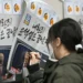 A woman writes on a poster showing South Korea President Yoon Suk Yeol, with text that reads 'insurrection criminal Yoon is over' (ANTHONY WALLACE) (ANTHONY WALLACE/AFP/AFP)